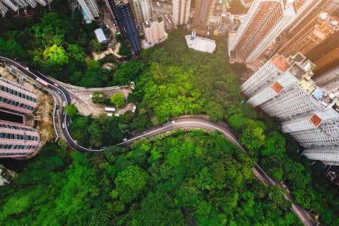 Aerial view of curve road in forest against buildings in Hong Kong